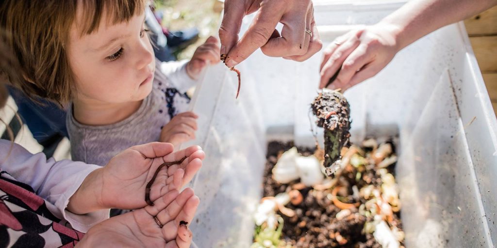 Home composting involves also children. Children looking at worms that help composting.