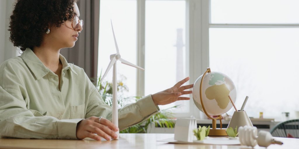 A woman by a table with a globe and windmill model in hands.