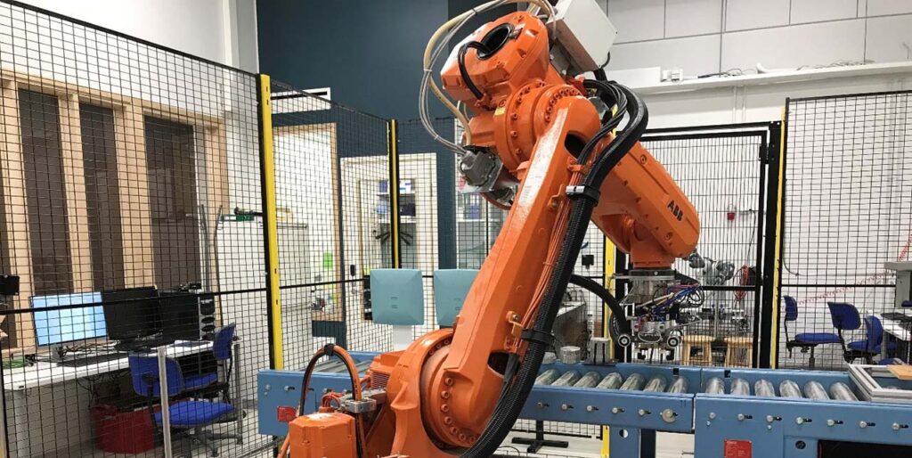 Kuvassa oranssi ABB:n teollisuusrobotti, joka on turvahäkissä turvallisuuden varmistamiseksi.
