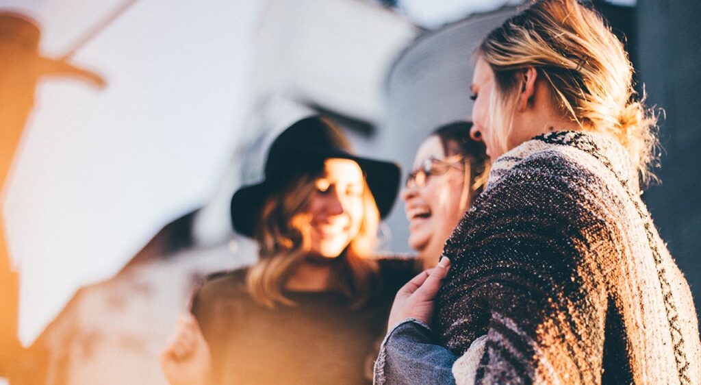 [Alt text: Three young ladies smiling and laughing together.]