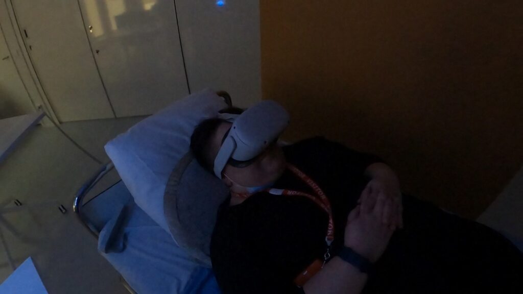 [Alt-teksti: Henkilö makaa sairaalasängyssä VR-lasit päässään.]