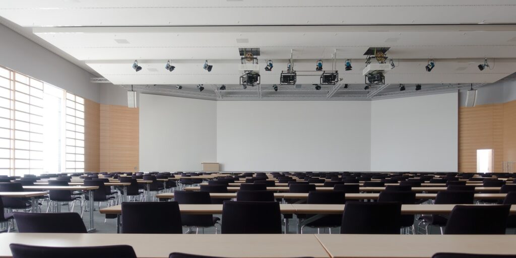 A photo of an empty conference room, with endless rows of tables and chairs.