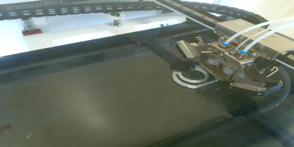 3D-tulostus käynnissä, kuvassa näkyy, kun 3D-tulostimen ekstruuderi lisää vaaleasävyistä sulaa muovia kerros kerrokselta. 