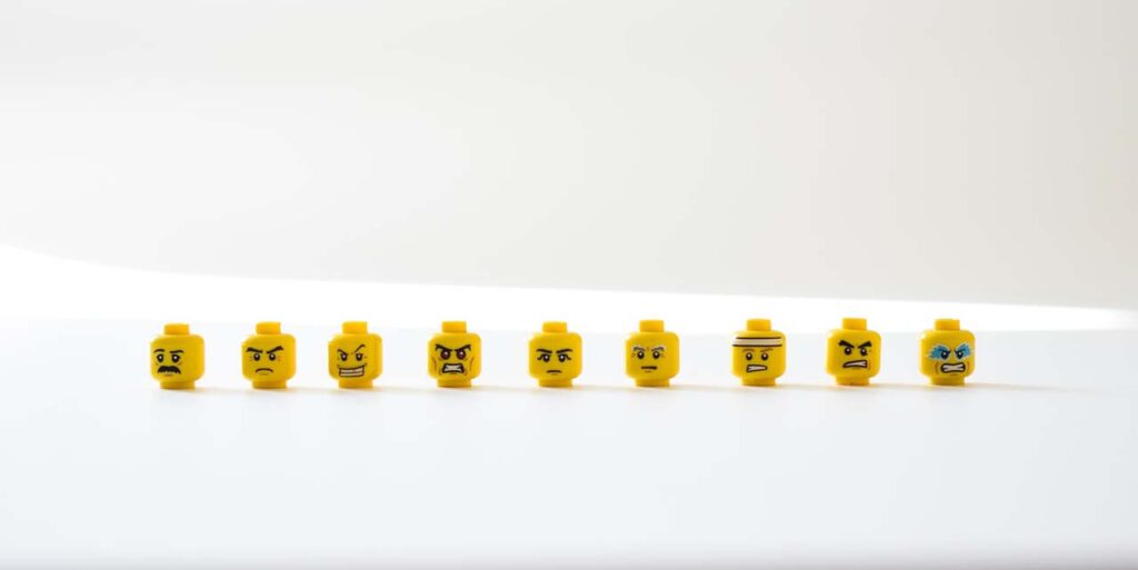 9 Lego hahmojen päitä joilla erilaiset ilmeet. Nämä muovilelut ilmentävät eri tunnetiloja 
