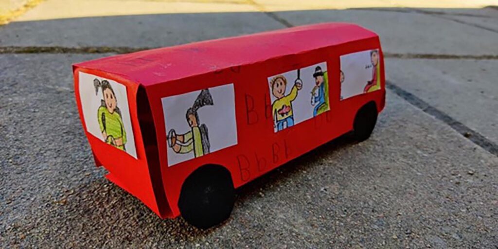 [Alt-teksti: Kuvassa on lasten pahvista askartelema bussi matkustajineen.]