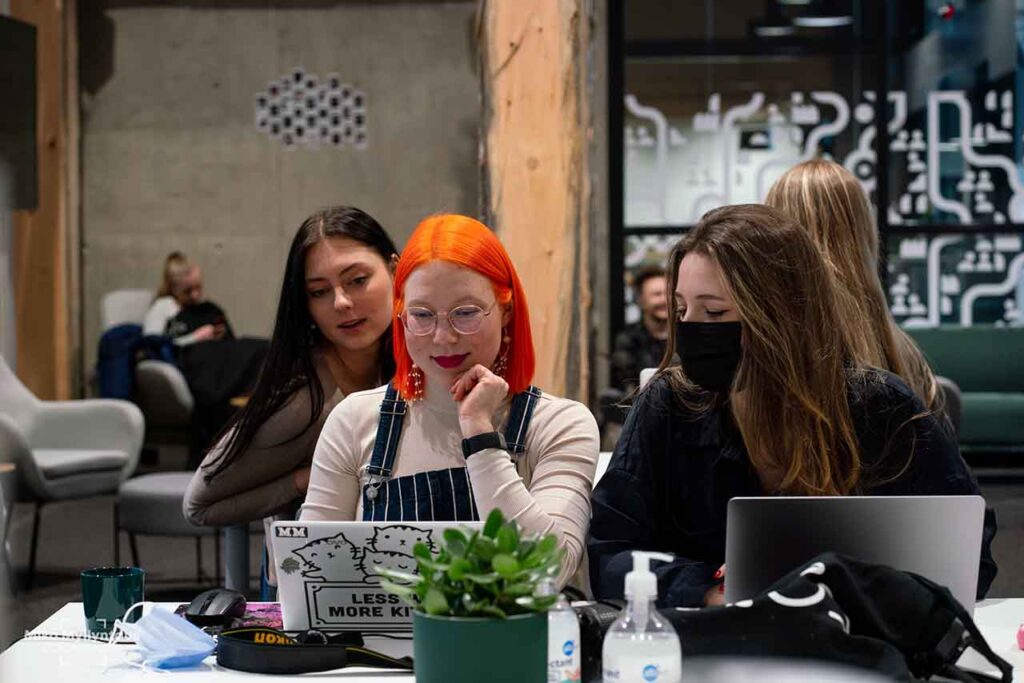 [Alt-teksti: Nuoria naisia pöydän ääressä tutkimassa kannettavia tietokoneitaan hymyillen.]