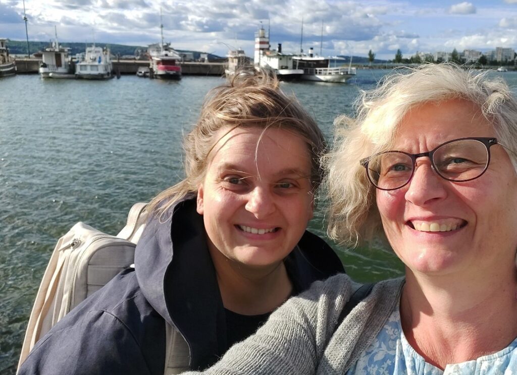 Authors Babette Sperling and Paula Nurminen standing in the front of the Vesijärvi lake in the harbor of Lahti city.