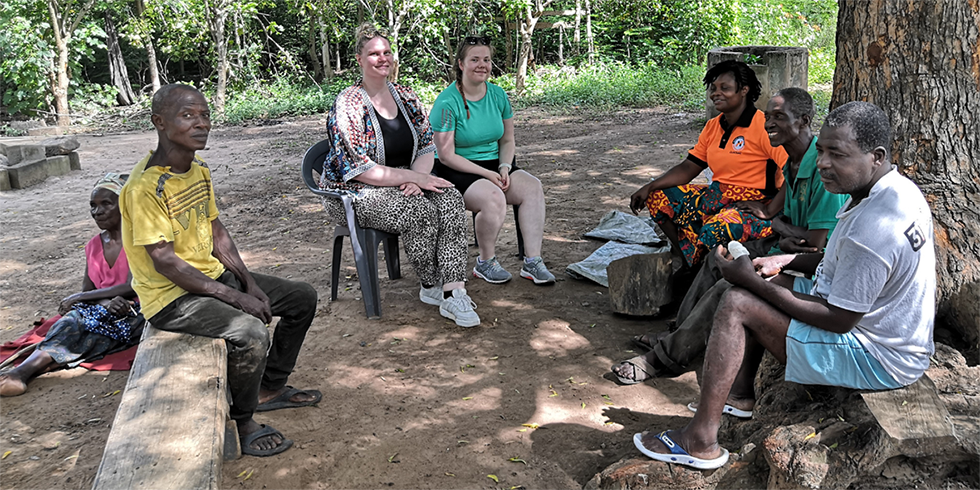 People sitting under a tree in an African village