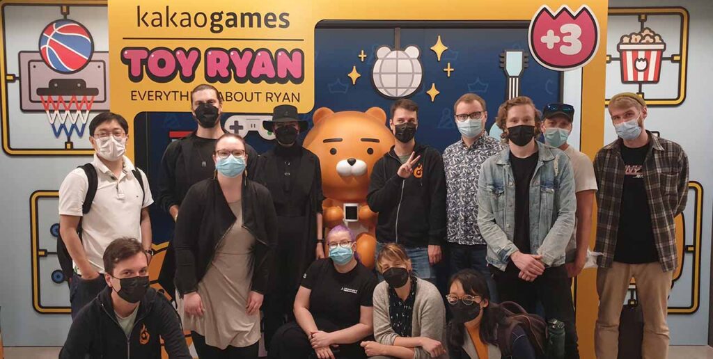 [Alt Text: Picture of a group of people wearing masks. In the background the text “Kakao Games – Toy Ryan”]