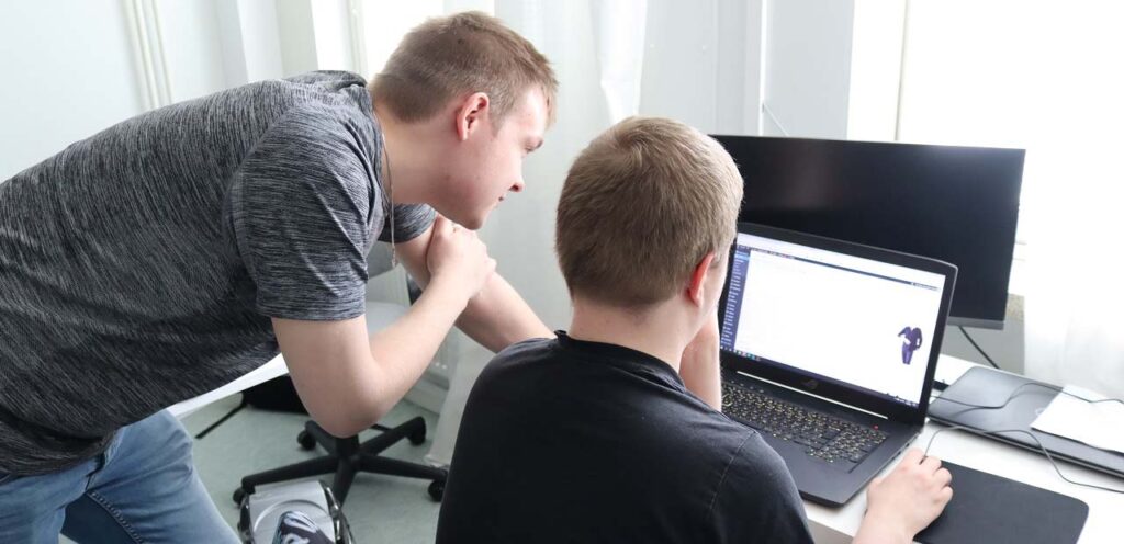 [Alt-teksti: Kaksi nuorta miestä avatun tietokoneen näyttöä tutkimassa.]