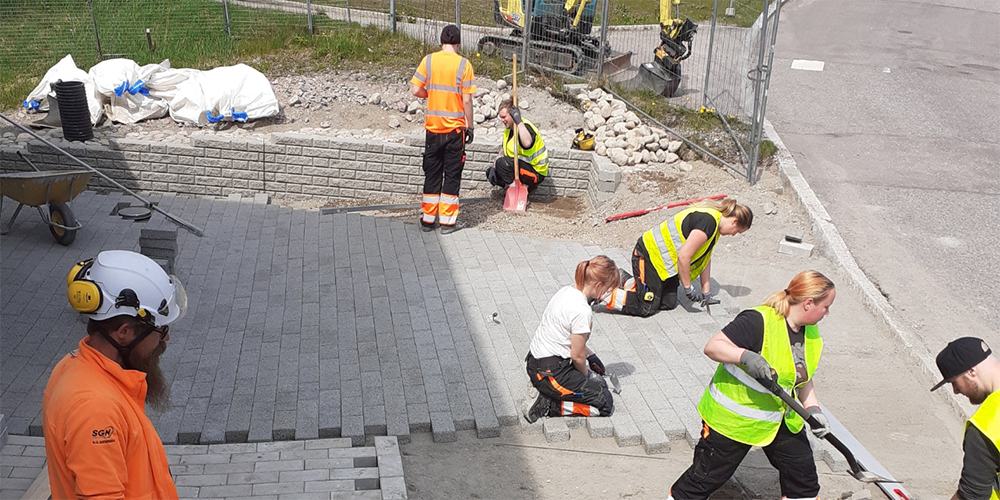 A stormwater system construction site. Workers with shovels and safety equipment.]