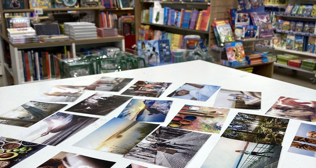 Pöytä kirjakaupassa. Pöydällä on levällään valokuvia, jotka liittyvät harrastuksiin ja muuhun mahdollisesti hyvinvointia tuottavaan tekemiseen tai oleiluun. 