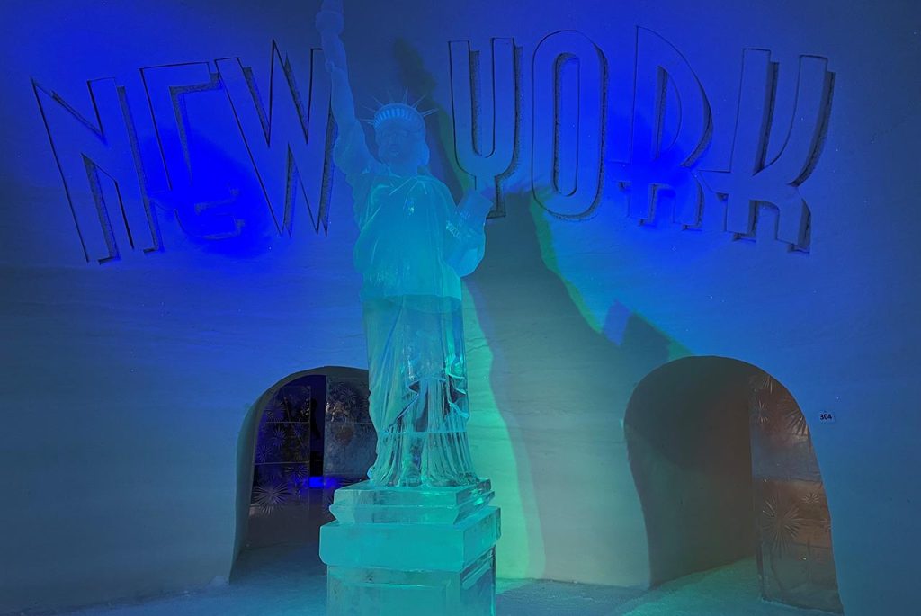 [Alt-teksti: hämyinen jääluola, jossa on värivalaistusta, lasinen vapaudenpatsas ja teksti new york.]