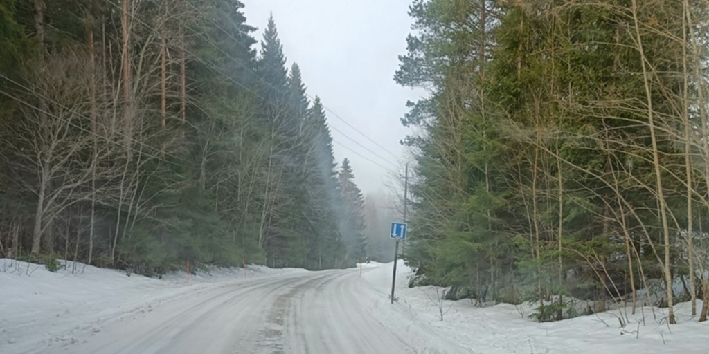 Jäinen ja luminen autio kylätie, metsää molemmin puolin tietä ja tien reunassa kohtaamispaikka-liikennemerkki.