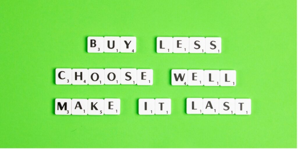 Kirkkaan vihreällä taustalla on tietokoneen näppäimistä muodostettu englanninkielinen lause Buy less, choose well, make it last. 