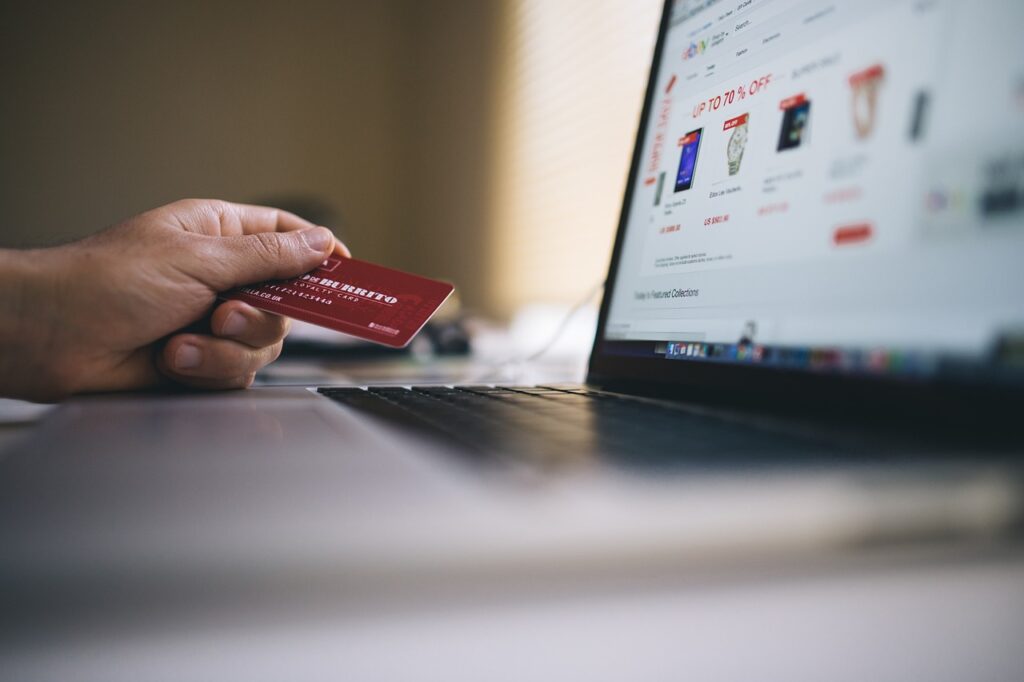 A hand holding a credit card and browsing an online store.