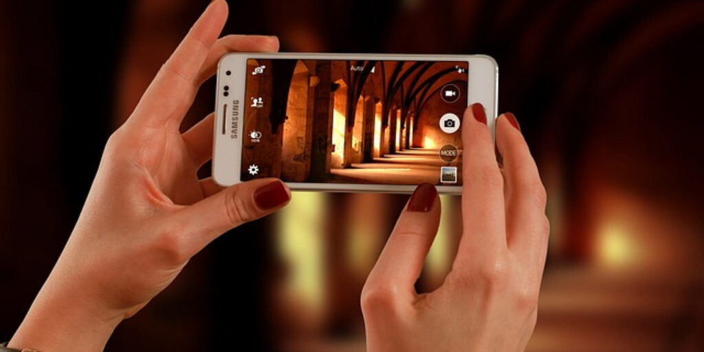 Naisen kädet, jotka valokuvaavat älypuhelimella valaistua tunnelia.