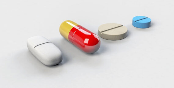 [ALT: Kuvassa yksi valkoinen ja yksi keltapunainen lääkekapseli sekä yksi pyöreä tabletti rivissä tasolla.]