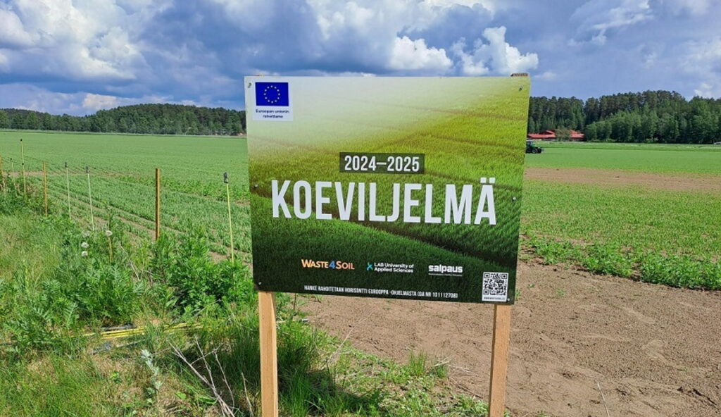 Kyltti tekstillä 2024–2025 Koeviljelmä; kyltissä EU-lippulogo, hankelogo sekä LABin ja koulutuskeskus Salpauksen logot. 