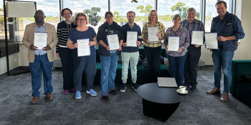 Eight teachers from different countries keeping received Erasmus certificates in their hands. 