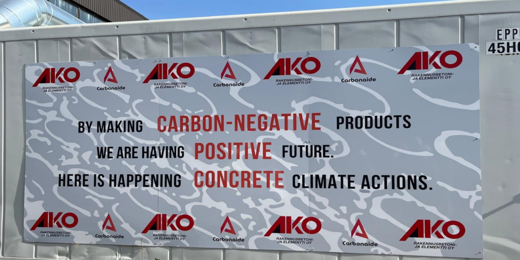 Tuotantokontin seinälle asetettu juliste, jossa lukee “By making carbon-negative products, we are having positive future, here is happening concrete climate actions”