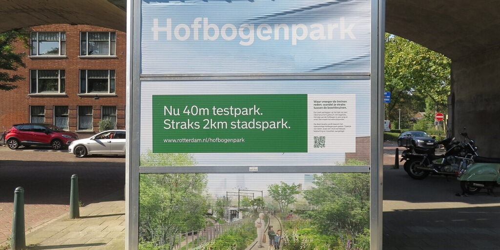 An infoboard in city surroundings. The text on the board says “Hofbogenpark.”