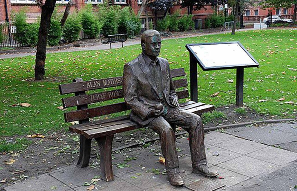 [Alt text: a statue, man sitting on a bench near the park.]