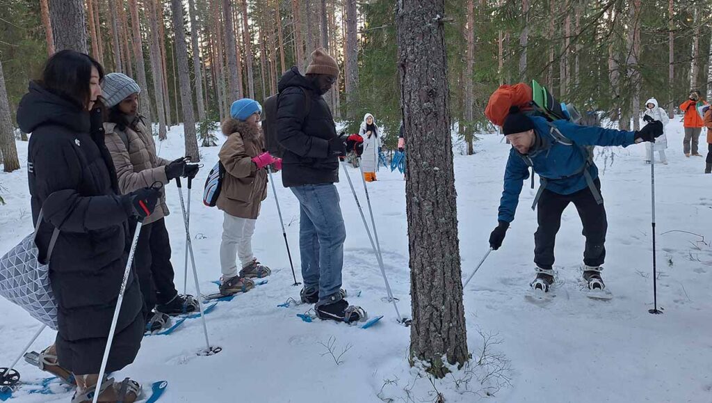 [Alt-teksti: Joukko ihmisiä on metsässä lumikenkäilemässä.]