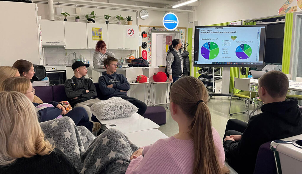 [Alt-teksti: suuri luokkatila, jossa nuoret kuuntelevat esitystä.]