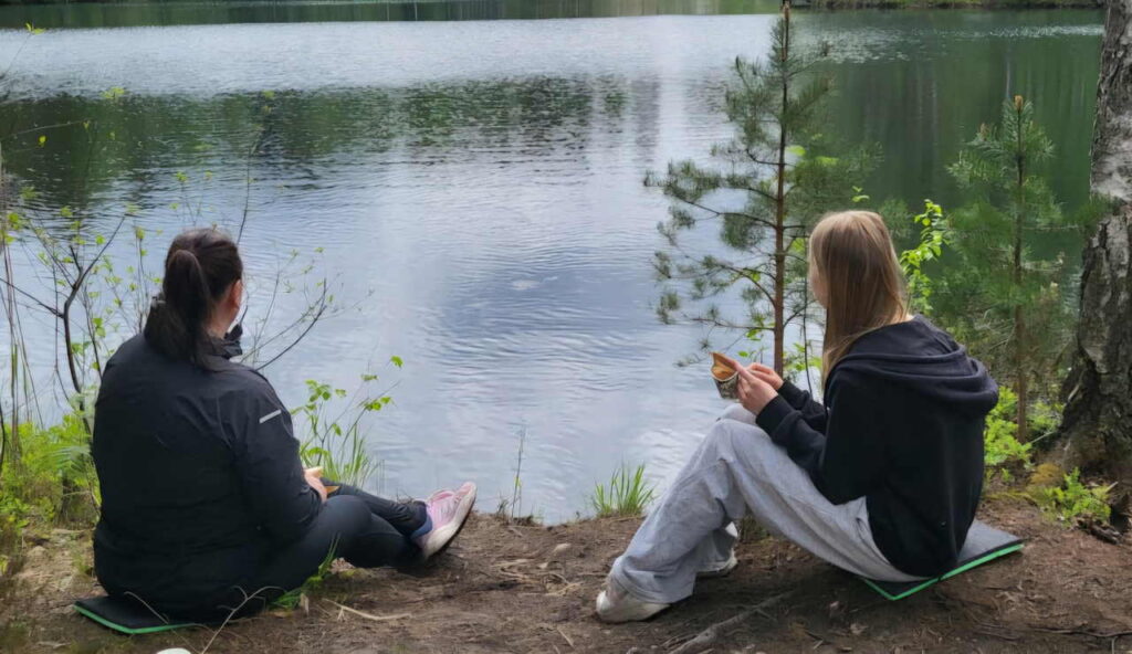 Kaksi ihmistä istumassa järven rannalla.