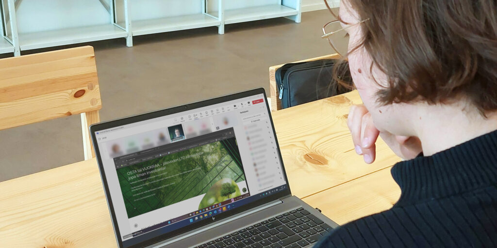 Henkilö katsoo tietokoneen näyttöä, jossa on Teams-yhteys. Puheenvuoron pitäjä jakaa näyttöä, jossa yrityksen nettisivut.
