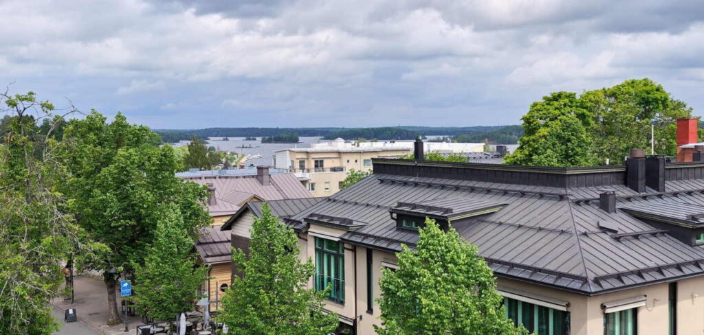 Kesäinen kaupunkimaisema Lappeenrannasta. Etualalla pienyrityskiinteistöjen kattoja ja taka-alalla Saimaa.
