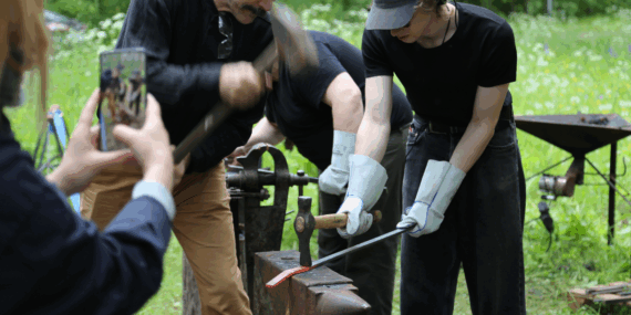Students hammering iron outdoors