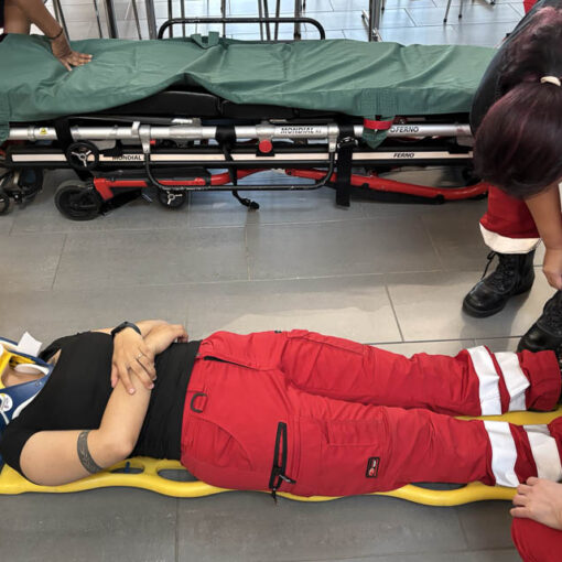 [Alt: Ensihoitaja makaa paareilla harjoitustehtävän aikana.]