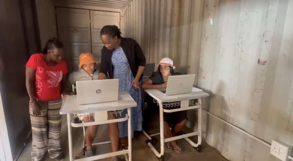 [Alt text: four persons in a room, two persons are working with laptops.]