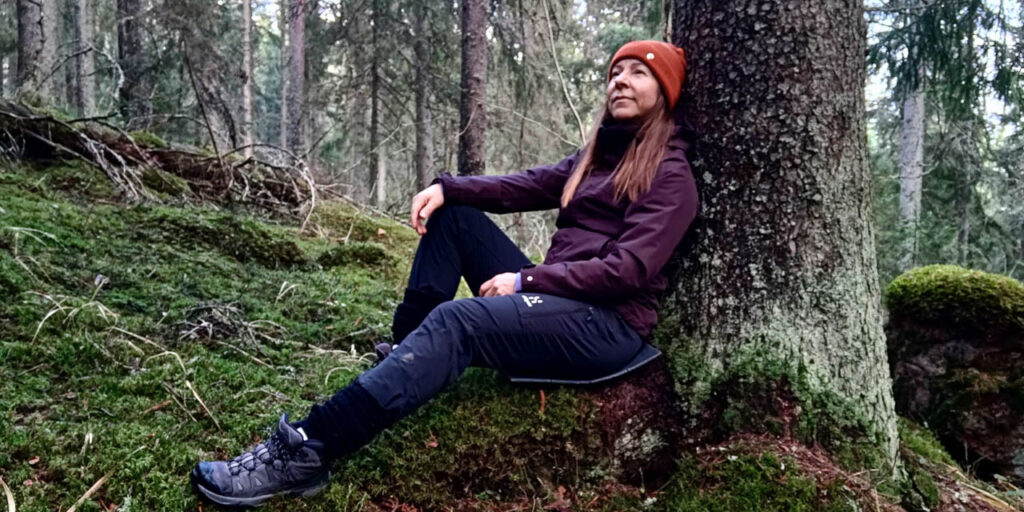 [Alt-teksti: Nainen istuu puun juurella metsässä.]