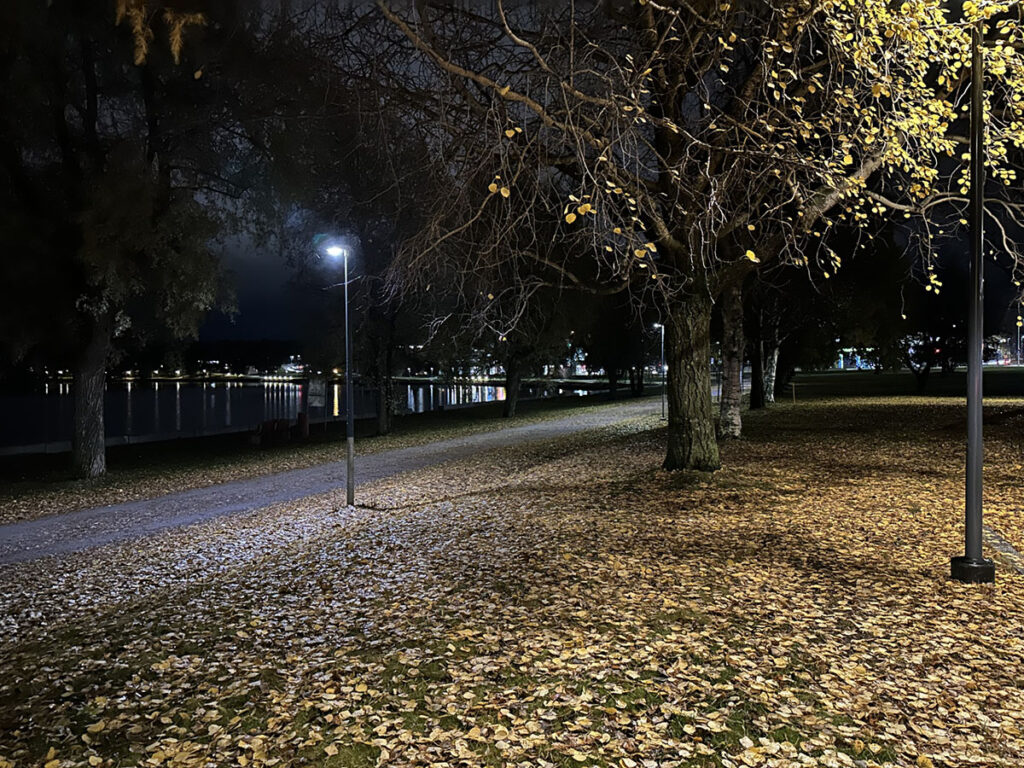 Syksyinen pimeä maisema, kävelytie vesistön varrella.