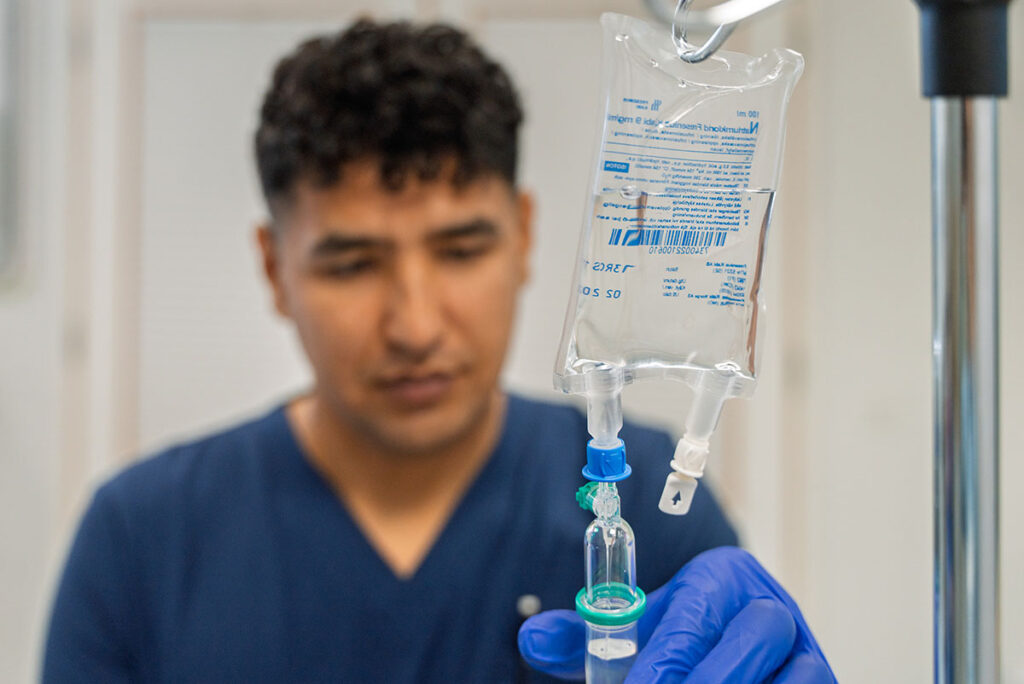 Sairaanhoitaja laittaa tippapussia.