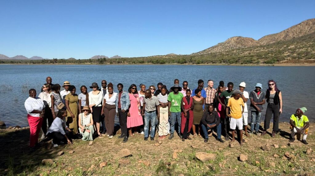 [Alt text: twenty people or so standing by the lake.]