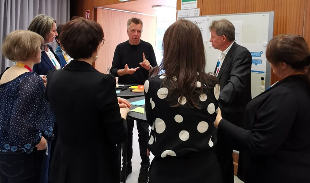 [Alt-teksti: ryhmä ihmisiä pöydän ääressä keskustelemassa.]