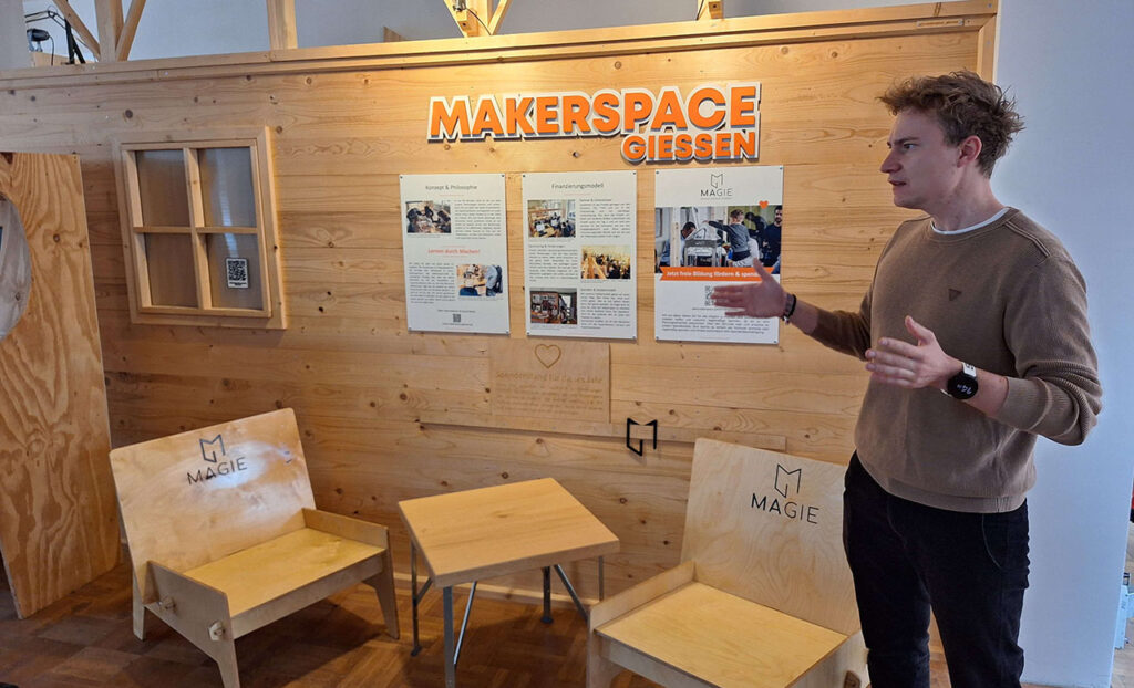 [Alt text: a man having a presentation in front of wooden furniture.]