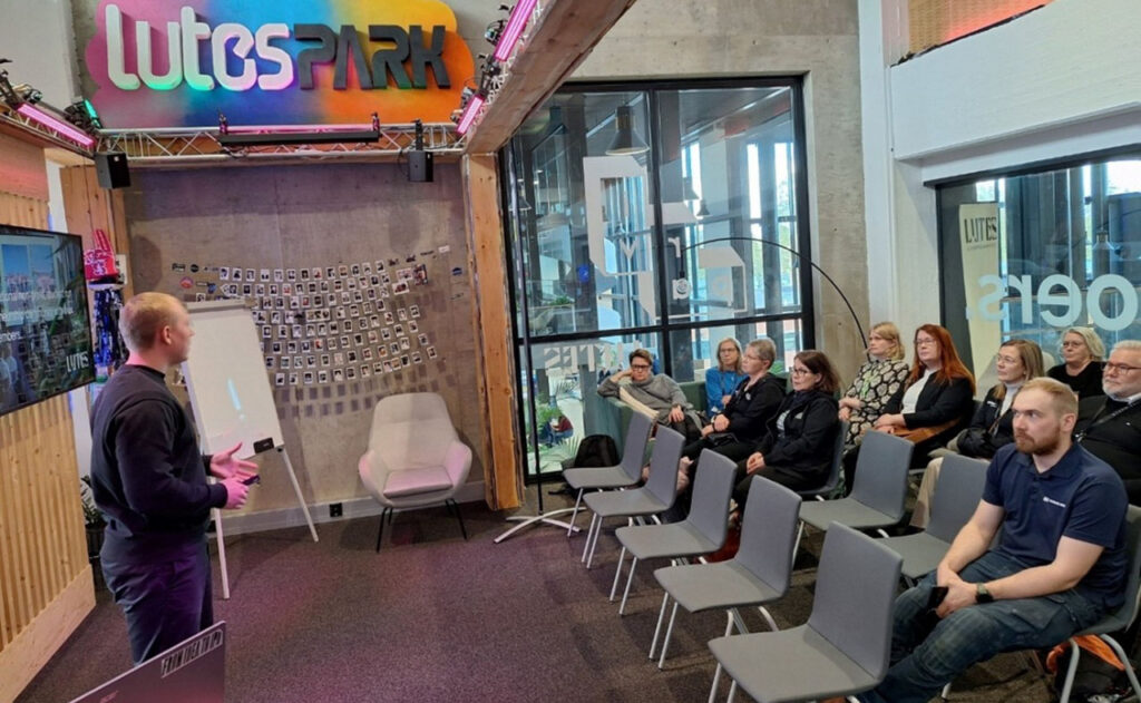 [Alt-teksti: henkilö pitämässä esitystä kuulijakunnalle.]