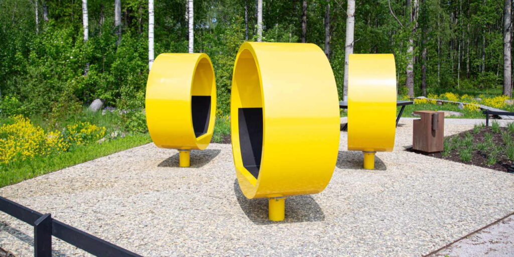 Puisto, jossa kolme keltaista pyöreää penkkiä.