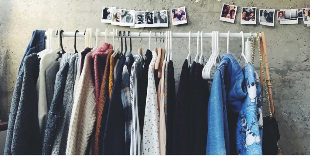 Vaaterekki, jossa erilaisia vaatekappaleita ja asusteita roikkuu hengareissa.