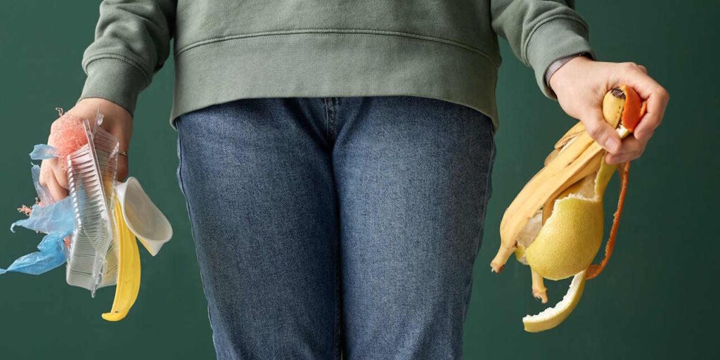 A person holding plastic and organic waste in hands.