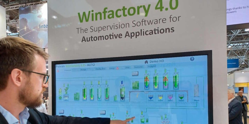 Henkilö osoittaa näyttöruutua, jossa esitellään kierrätysprosessin kulkua.