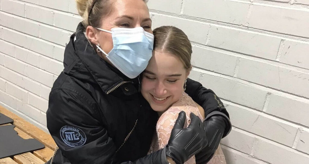 [Alt-teksti: Valmentaja halaa taitoluistelijaa.]