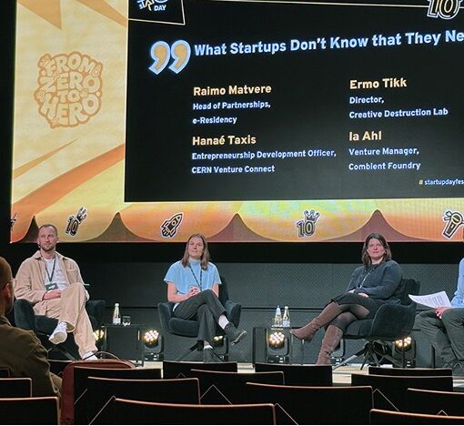A group of panel attendees sitting on a stage at a startup conference.