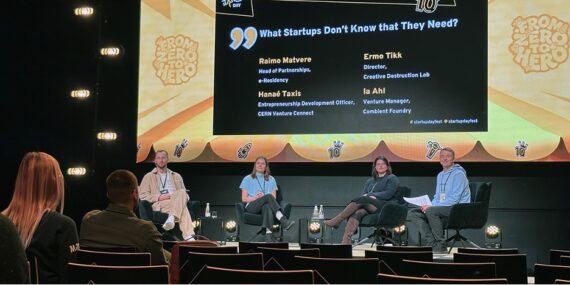 A group of panel attendees sitting on a stage at a startup conference.