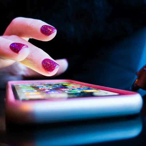 Lähikuva kädestä, joka käyttää älypuhelinta tasaisella pinnalla; kosketusnäytön käyttö kuvaa arkista digipalvelun käyttötilannetta.